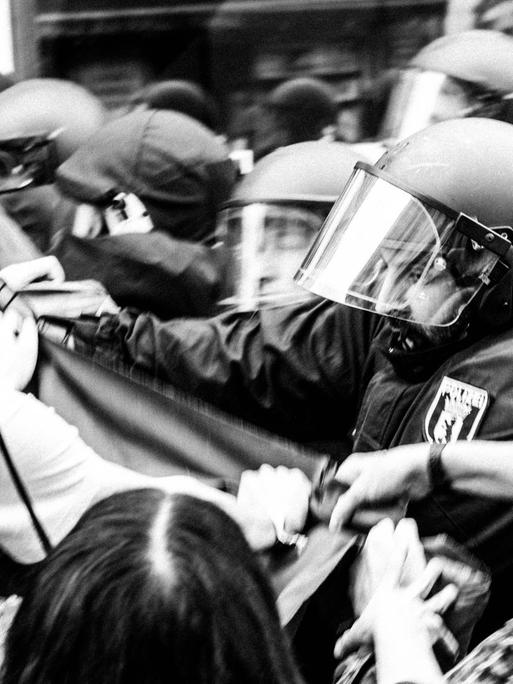 Schwarzweißfoto einer angespannt bis konkret stressigen Situation zwischen Polizei und Hausbesetzern.