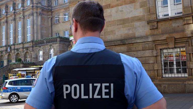 Ein Polizist steht am 16.05.2013 in Kassel (Hessen) vor dem wegen einer Bombendrohung abgesperrten und evakuierten Rathaus. Foto: Uwe Zucchi/dpa
