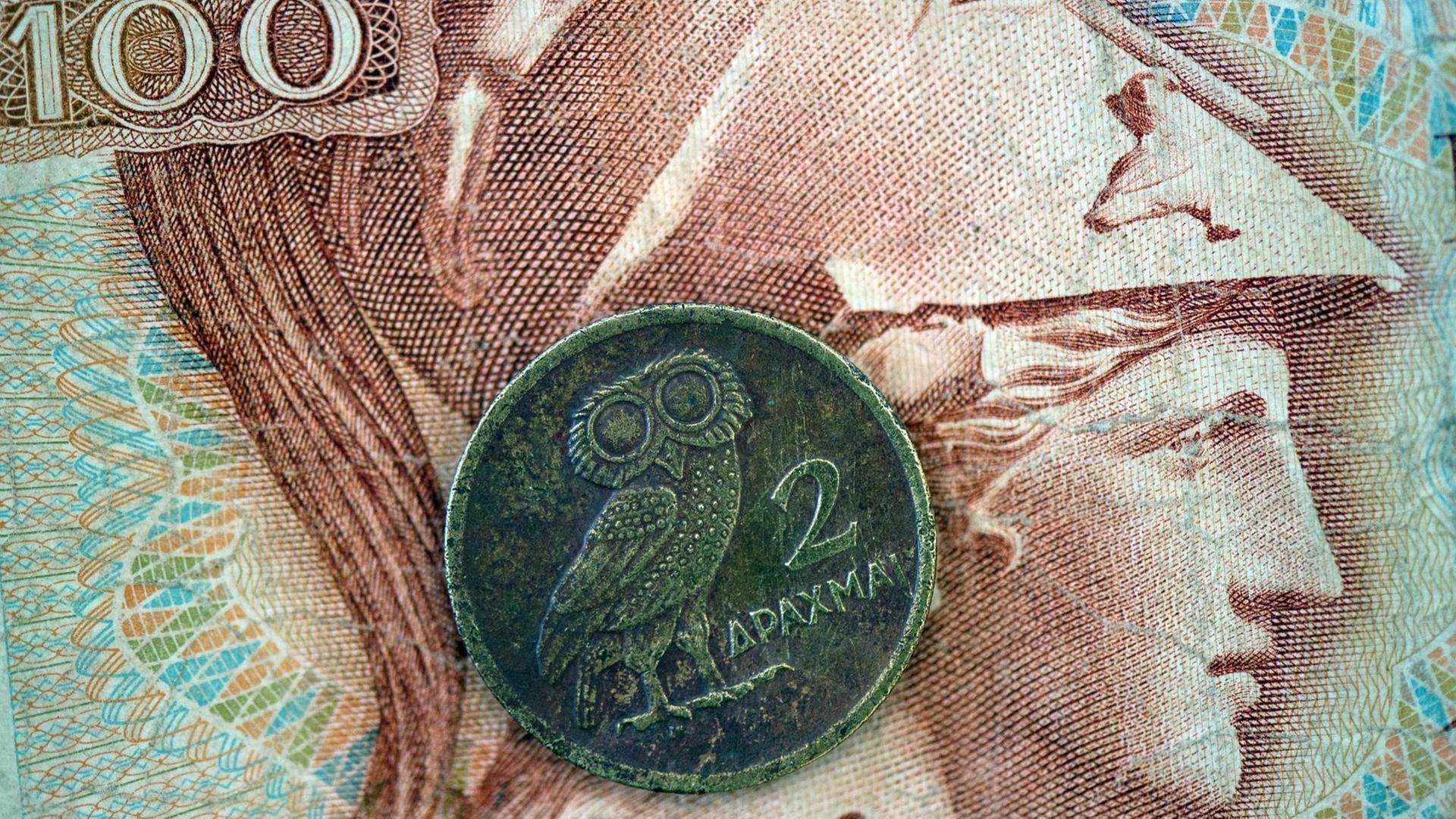 Eine griechische Drachmen-Münze liegt auf einem 100-Drachmen-Geldschein.