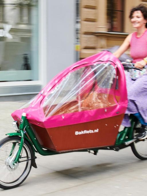 Eine Frau fährt mit einem Lastenrad durch Berlin.