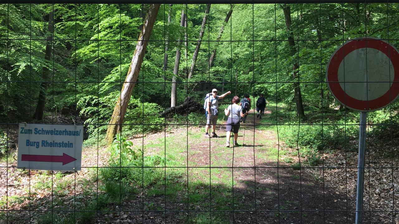Wanderer hinter einem Zaun hinter dem auch ein Verbotsschild steht