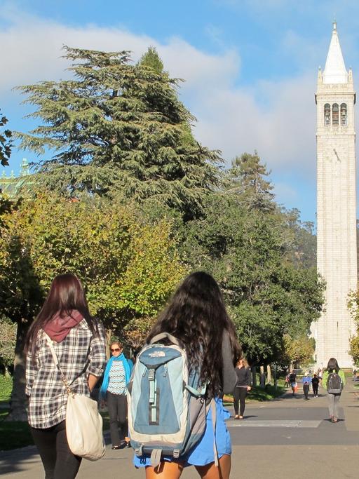 Studenten gehen über den Campus der Universität in Berkeley mit dem Campanile, einem Glockenturm und Wahrzeichen des Gebäudes.