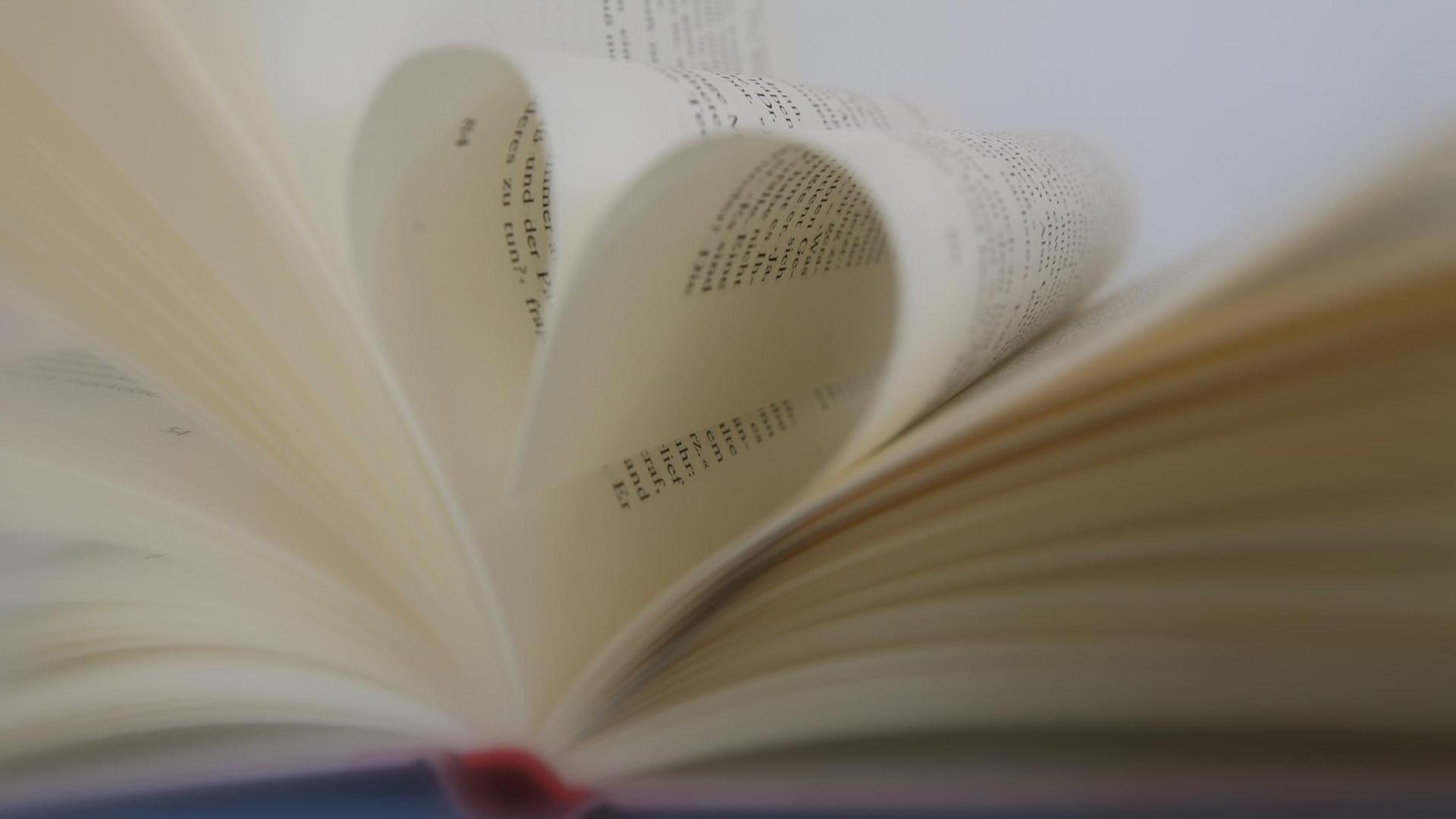 Liebesgeschichte Roman herzförmige Seiten - Die Buchseiten eines Liebesromans sind in Herzform gegeklappt.