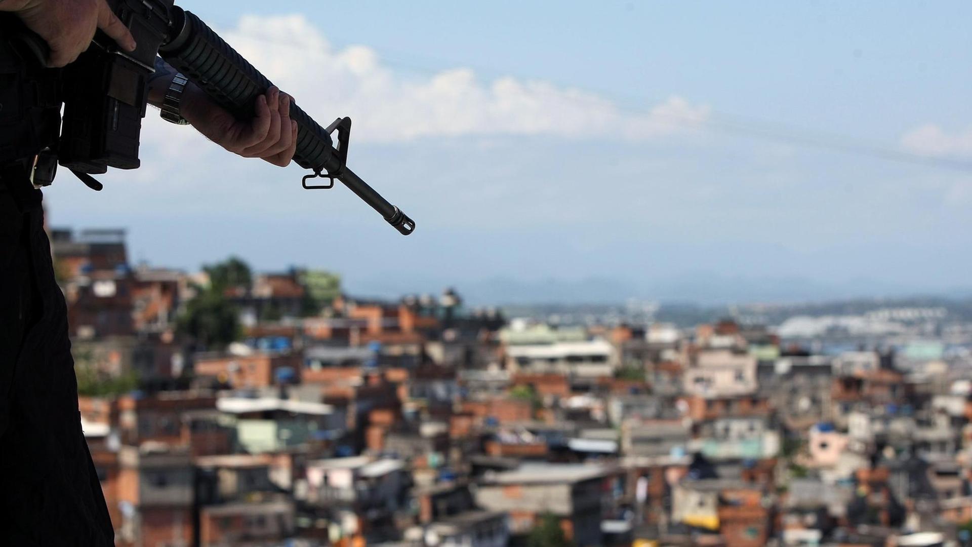Ein brasilianischer Soldat hält ein Maschinengewehr in der Hand - im Hintergrund ist ein Armenviertel von Rio de Janeiro zu sehen.