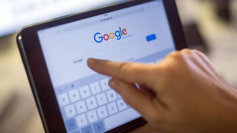 Ein Finger zeigt auf einem iPad auf das Google-Suchfeld.