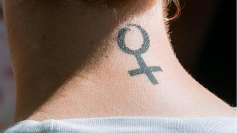 Eine Frau in Hamburg trägt das Frauenzeichen, den Venusspiegel, als Tattoo auf ihrem Nacken.