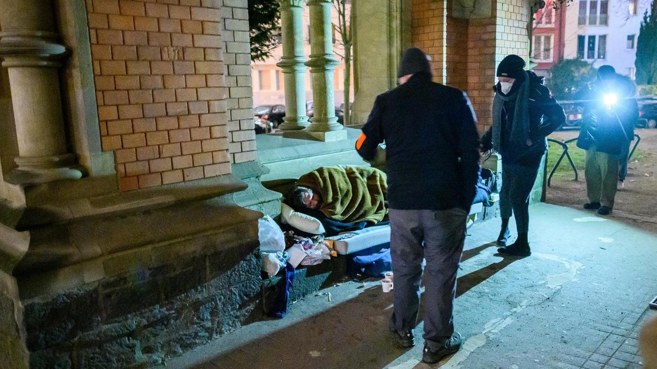 Zwei Sozialarbeiter vom Frankfurter Kältebus sehen nach einem Obdachlosen, der im Durchgang einer Kirche schläft. 