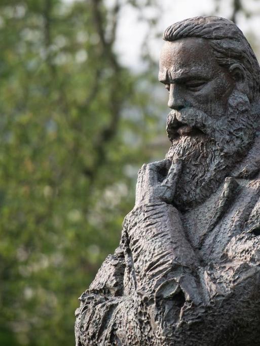 Die Statue Friedrich Engels' in Denkerpose ist ein Geschenk Chinas an die Stadt Wuppertal. Engels guckt nachdenklich zu Boden und streicht sich mit einer Hand den Bart.
