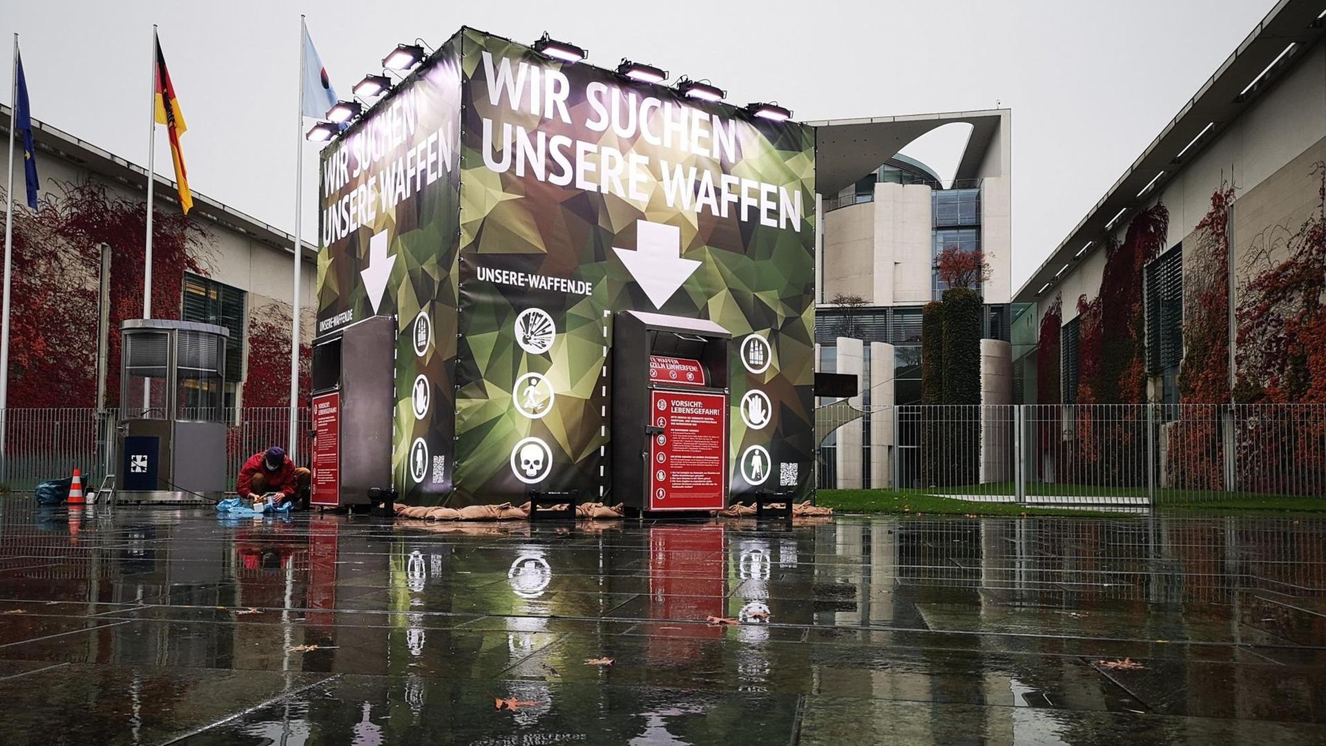Container in Tarnfarben mit der Aufschrift "Wir suchen unsere Waffen" vor dem Berliner Kanzleramt.
