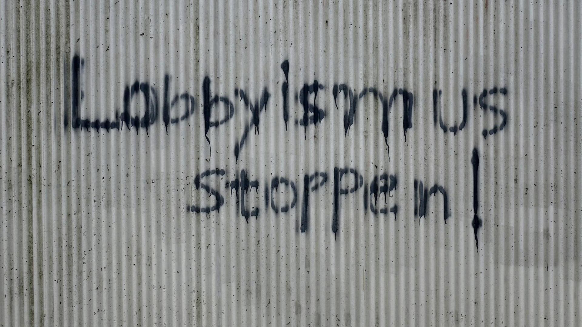Ein Graffiti mit der Aufschrift "Lobbyismus stoppen" steht an eine Hauswand gesprüht.