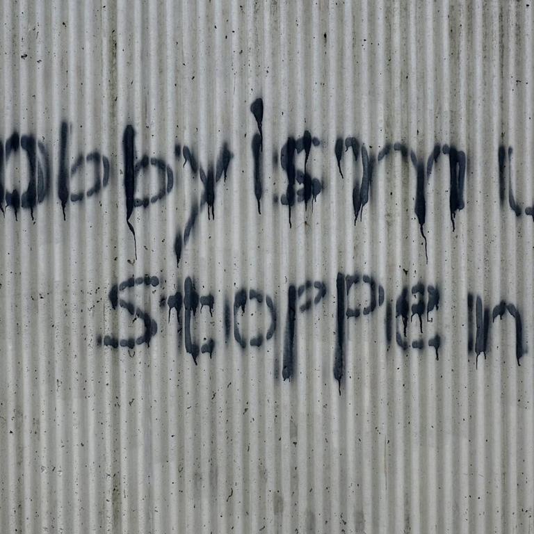 Ein Graffiti mit der Aufschrift "Lobbyismus stoppen" steht an eine Hauswand gesprüht.