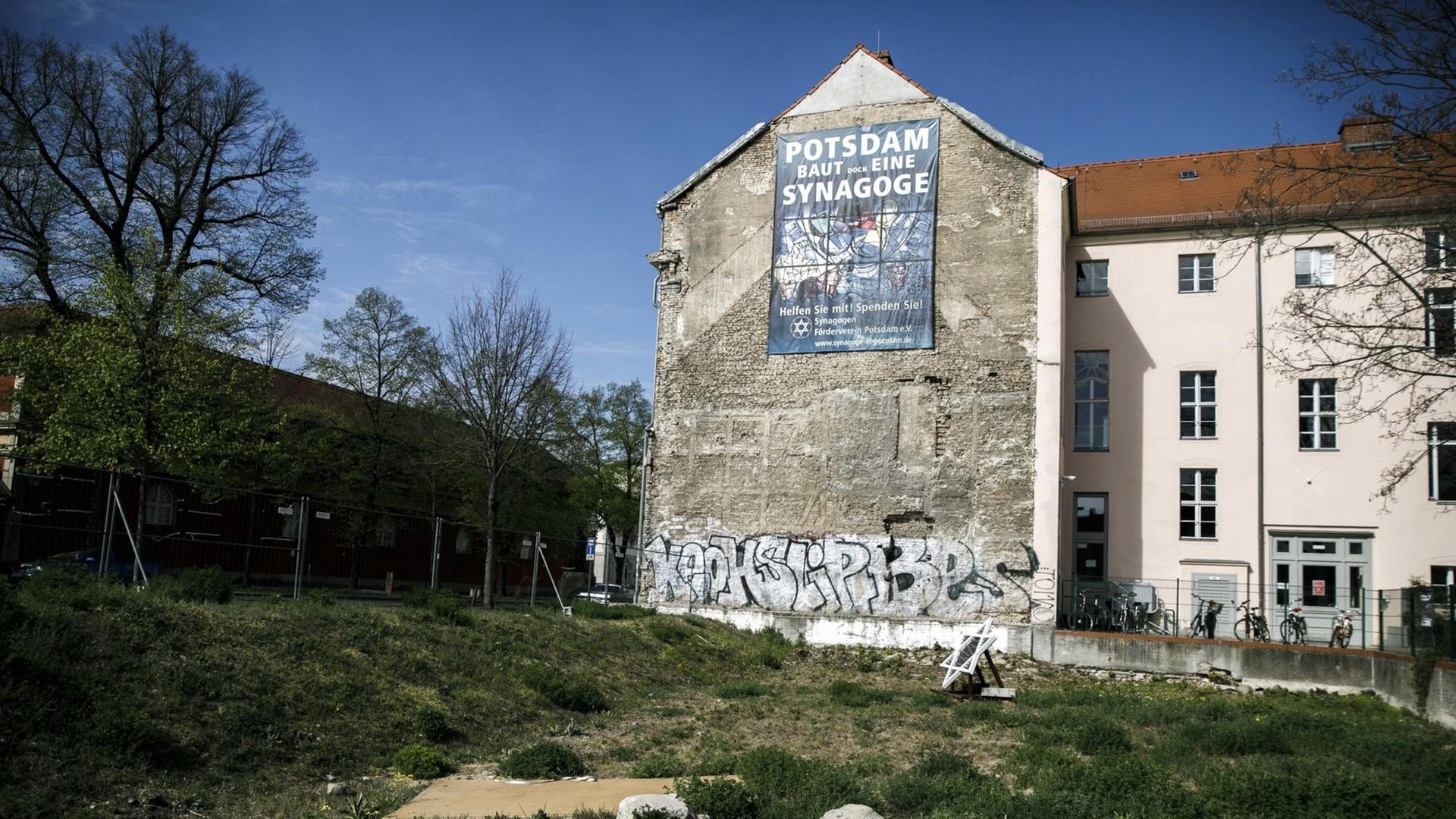 24.04.2020, Brandenburg, Potsdam: An der Mauer eines Wohnhauses hängt ein Plakat mit der Aufschrift "Potsdam baut doch eine Synagoge". Das Grundstück gegenüber dem Filmmuseum war vom Land Brandenburg für den Bau der Neuen Synagoge zur Verfügung gestellt worden.