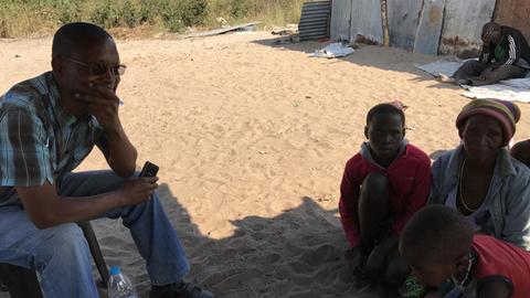 Bothas Marinda Xunudao erzählt im Dorf der Heilerin von seinem Weg aus seiner Heimat in Nordost-Namibia nach Deutschland und zurück