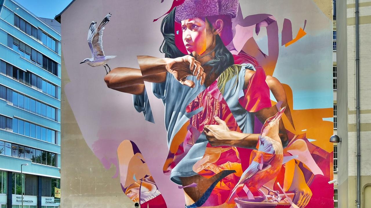 Wandbild: Eine Frau blickt in die Ferne, von ihrem Arm hebt eine Möwe ab.