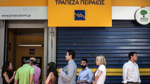 An einem Geldautomaten in Athen stehen mehrere Menschen an.