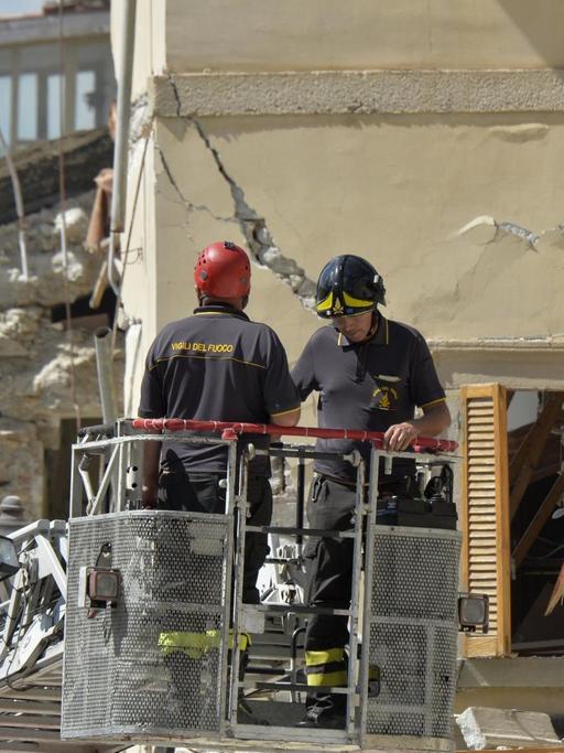 Feuerwehrleute untersuchen ein beschädigtes Gebäude in Amatrice.