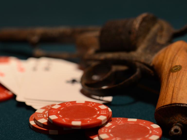 Im Kasino: Jetons und Spielkarten liegen vor einer Pistole.