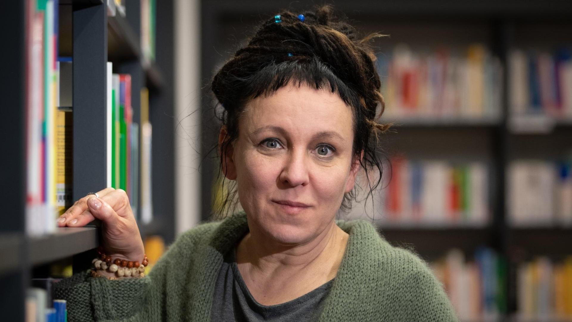 Die polnische Autorin Olga Tokarczuk steht an einem Bücherregal.