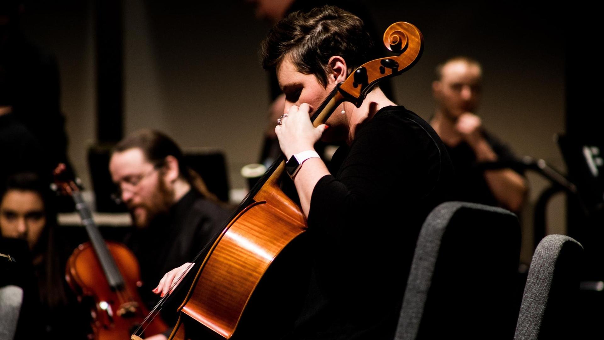 Im Bildvordergrund ist eine Cellistin zu sehen, im Hintergrund drei weitere Musiker mit Streichiinstrumenten.