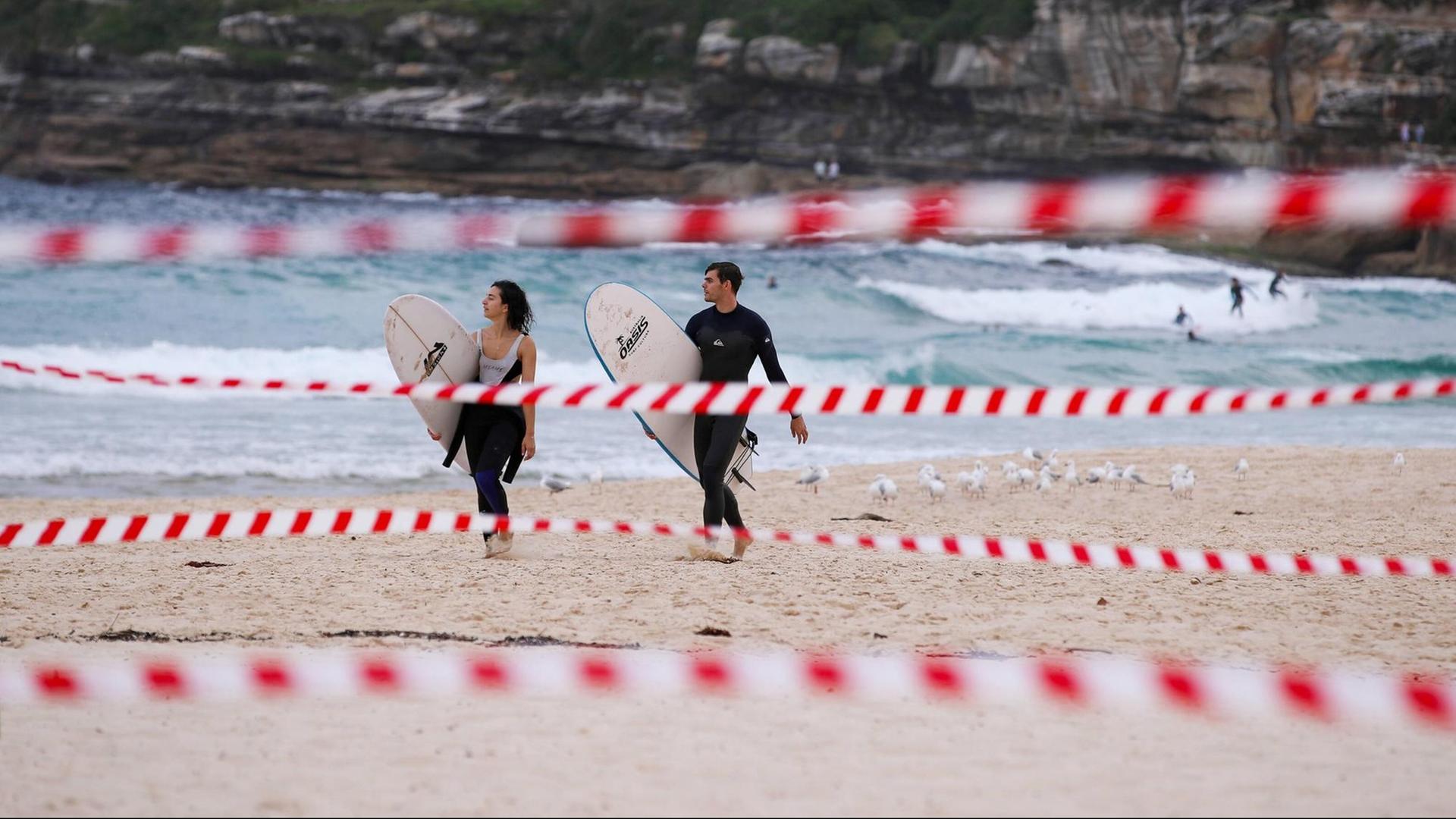 Eine wenige Surfer am Bondi Beach in Sydney, Australien, im Vordergrund ist Absperrband zu sehen, aufgenommen im April 2020