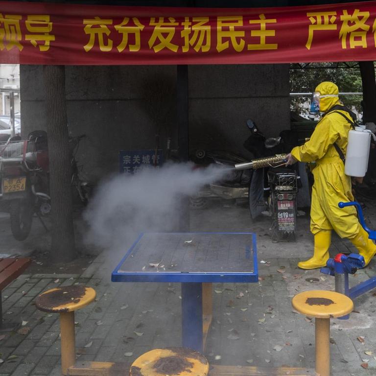 Das Bild zeigt einen Mann mit Schutzkleidung in der chinesischen Stadt Wuhan. Er desinfiziert mit eine Straße. STR / AFP) / China OUT