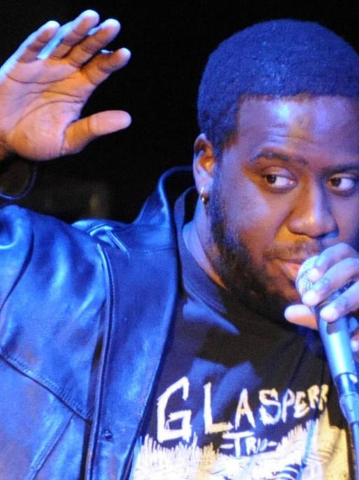 Robert Glasper singt in ein Mikrofon.
