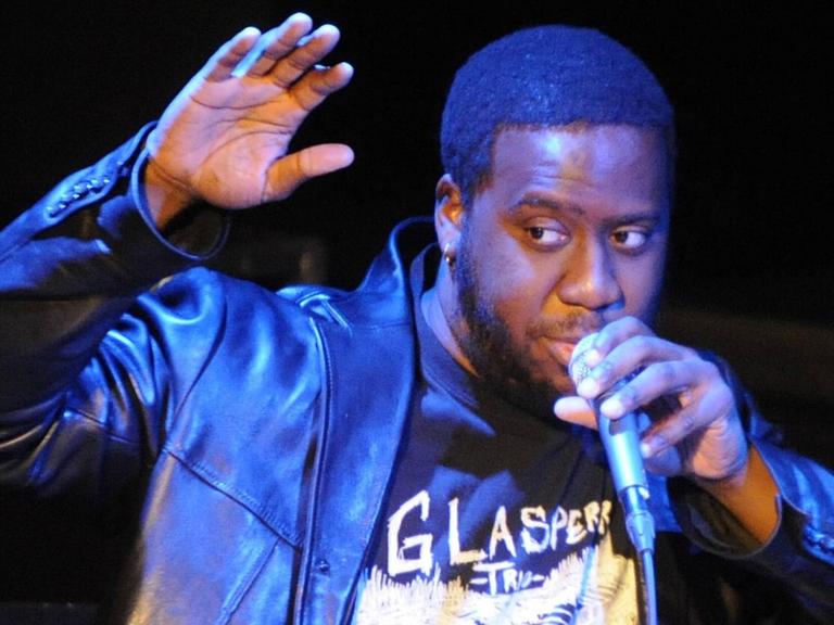 Robert Glasper singt in ein Mikrofon.