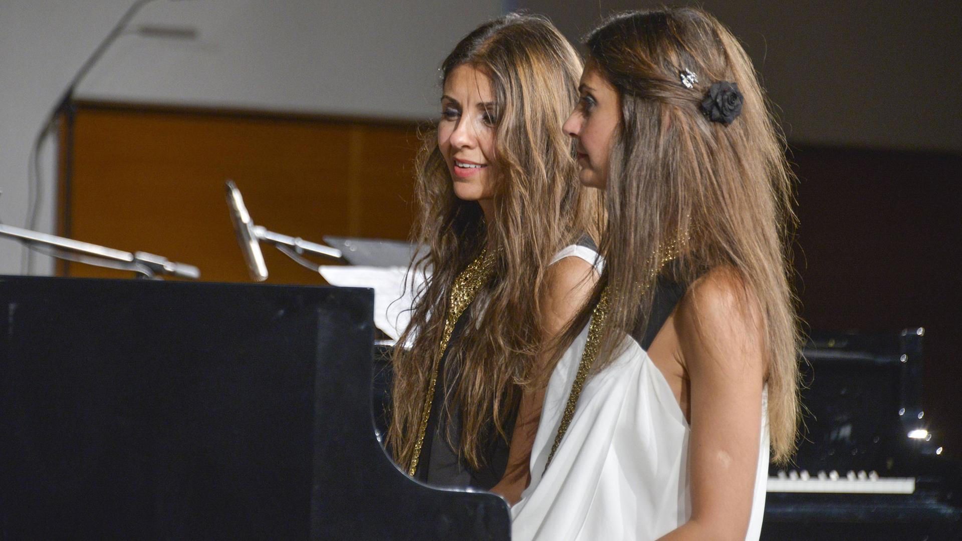 Die türkischen Pianistinnen und Zwillingsschwestern Ferhan und Ferzan Önder sitzen 2014 nebeinander an einem Flügel.