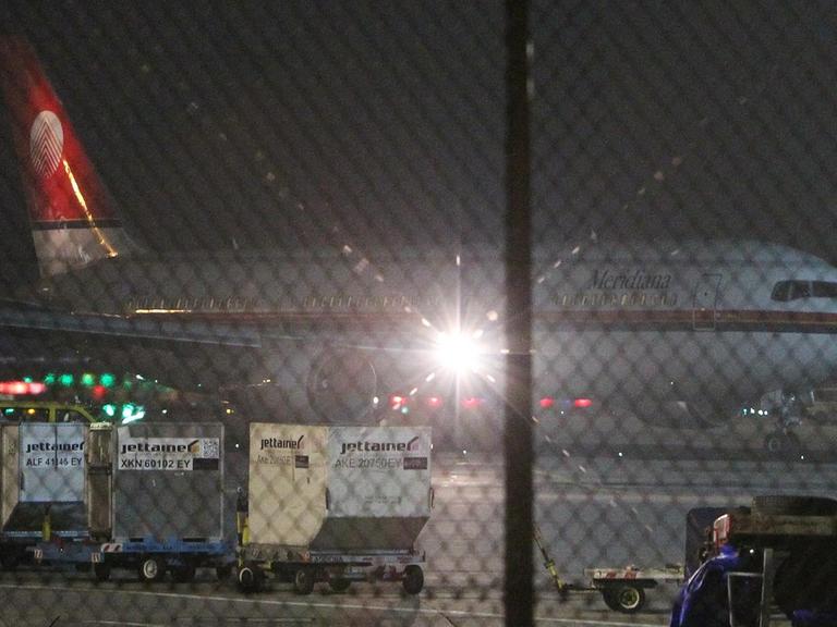 Das Flugzeug steht in der Dunkelheit hinter einem Zaun auf dem Frankfurter Flughafen. 