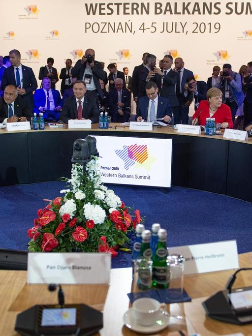 Bundeskanzlerin Angela Merkel sitzt in einem roten Jackett an einem großen runden Tisch zwischen weiteren Spitzenpolitikern der EU sowie der Staaten des Westbalkans-Staaten.