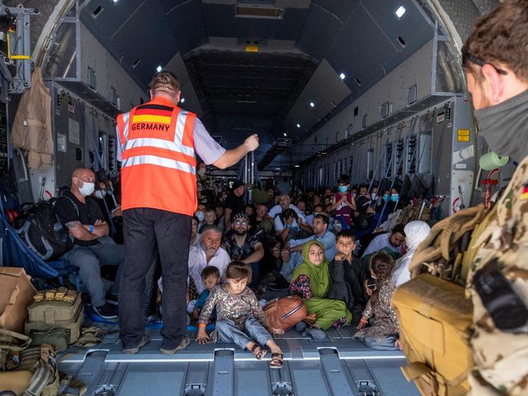 Eng gedrängte Flüchtende aus Afghanistan werden in einem Airbus der Bundeswehr von einem Koordinator mit Informationen versorgt.
