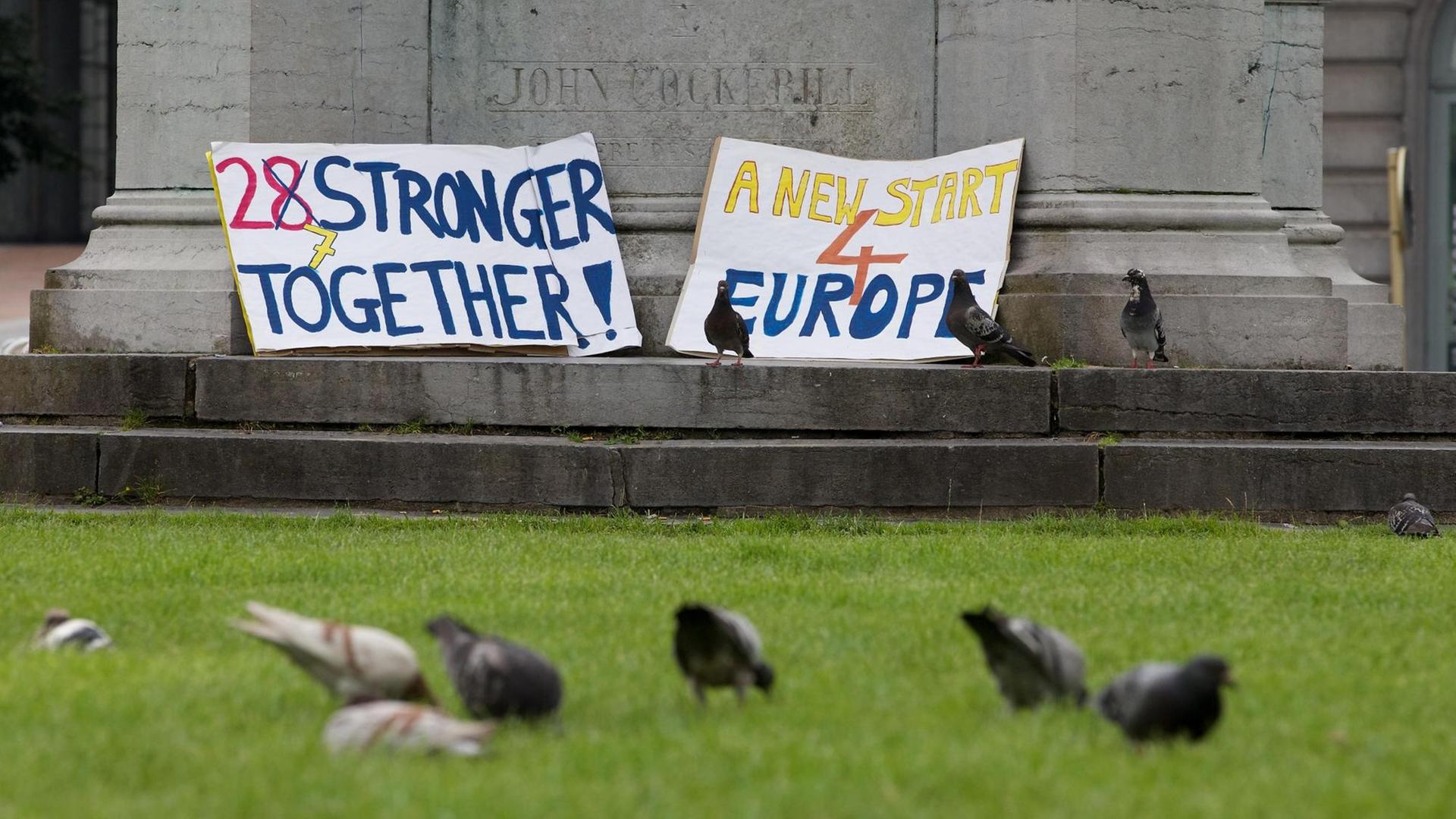 Nach dem Brexit-Referendum liegen zwei Plakate mit den Aufschriften "27 stronger together" und "A new start 4 Europe" vor einer Statue.