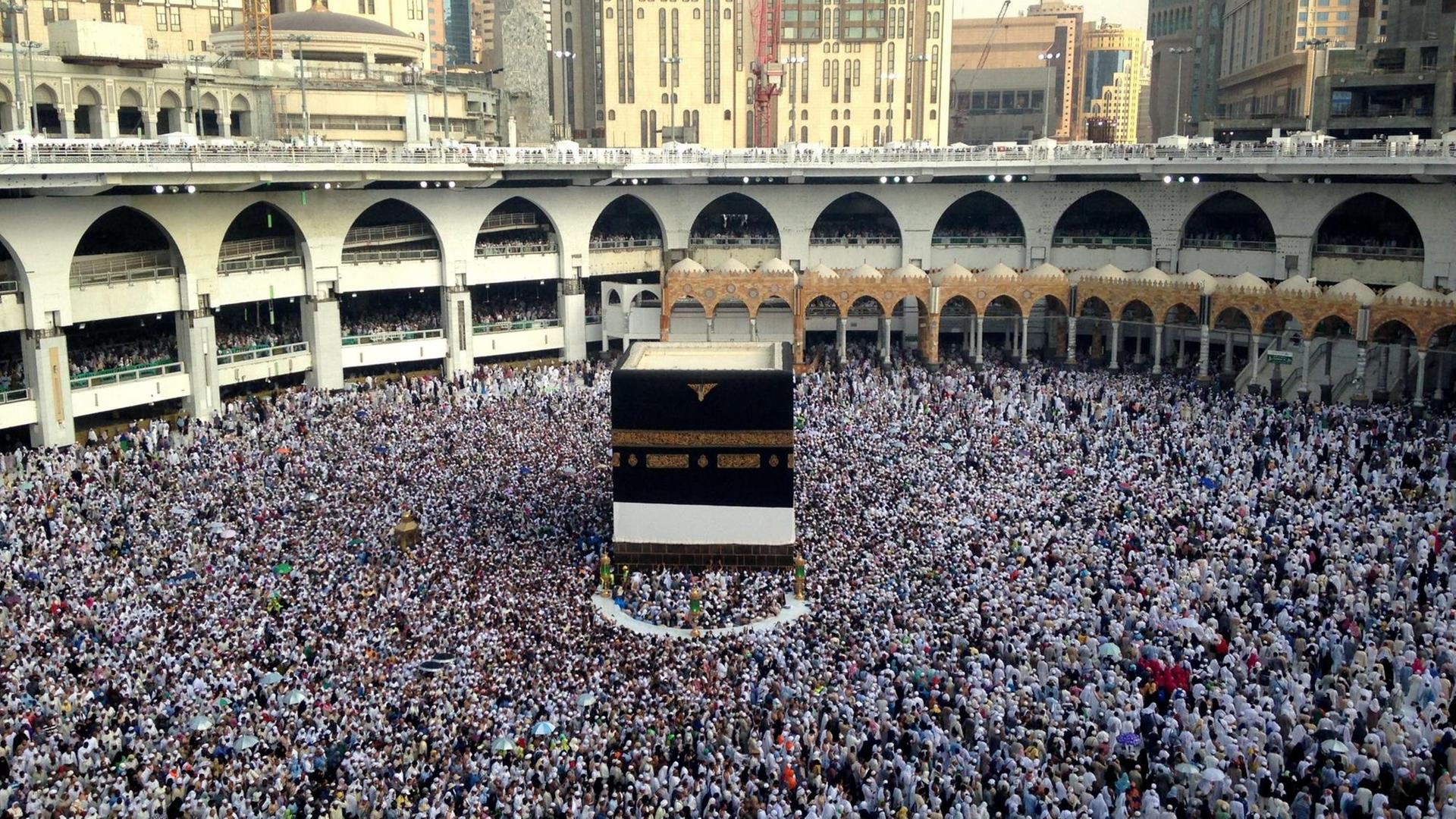 Die Große Moschee von Mekka mit der Kaaba in der Mitte und einer großen Menschen-Menge darum herum.