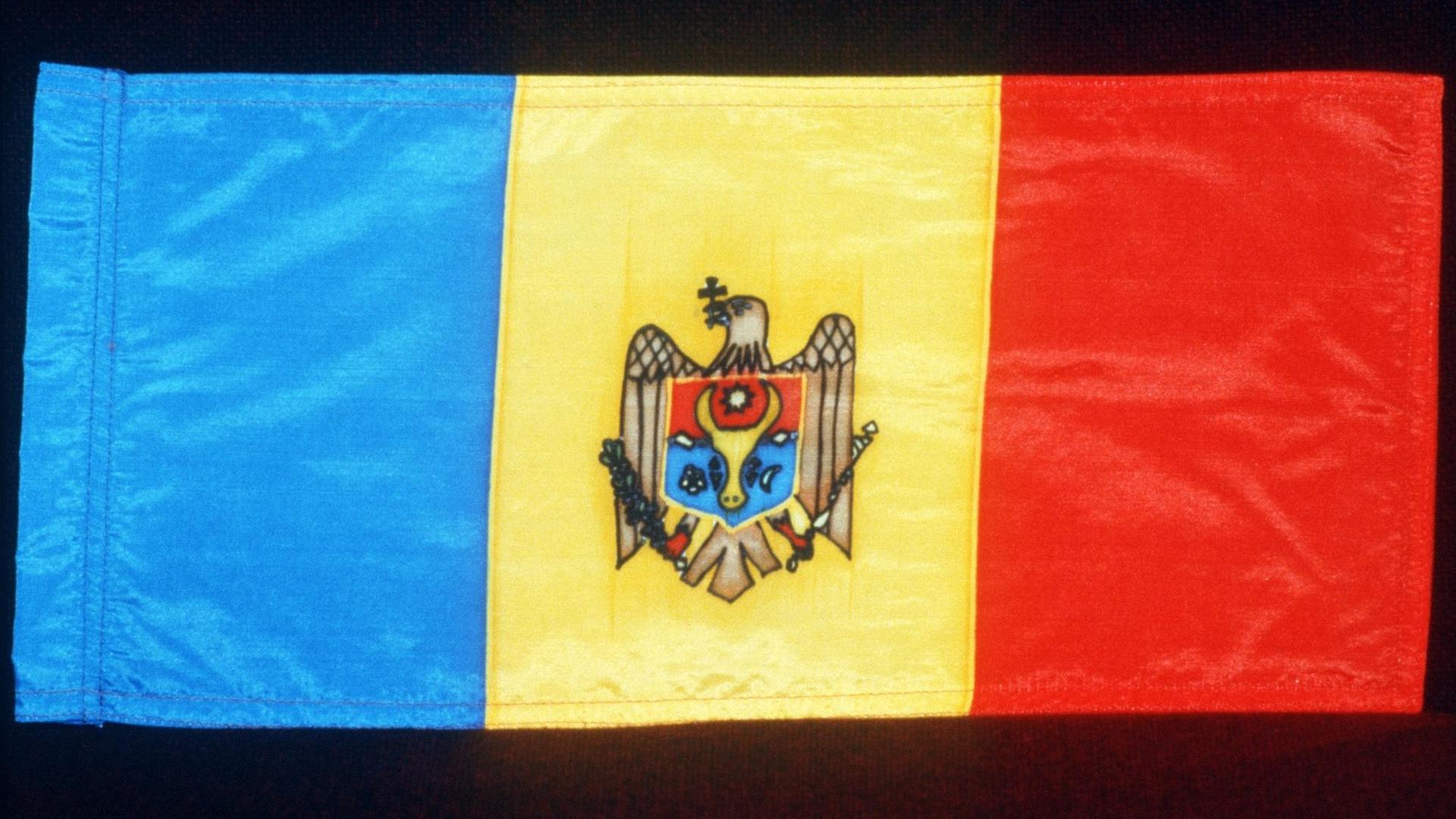 Die Flagge der Republik Moldau zeigt einen senkrechten blauen, einen gelben und einen roten Balken. auf dem gelben Balken befindet sich ein Wappen.