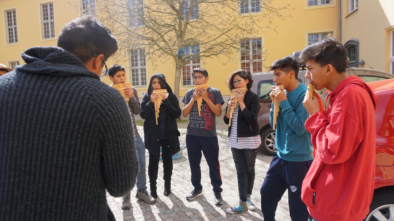Musiker des OEIN Orchesters spielen ihre Panflöten vor der Musikakademie Rheinsberg