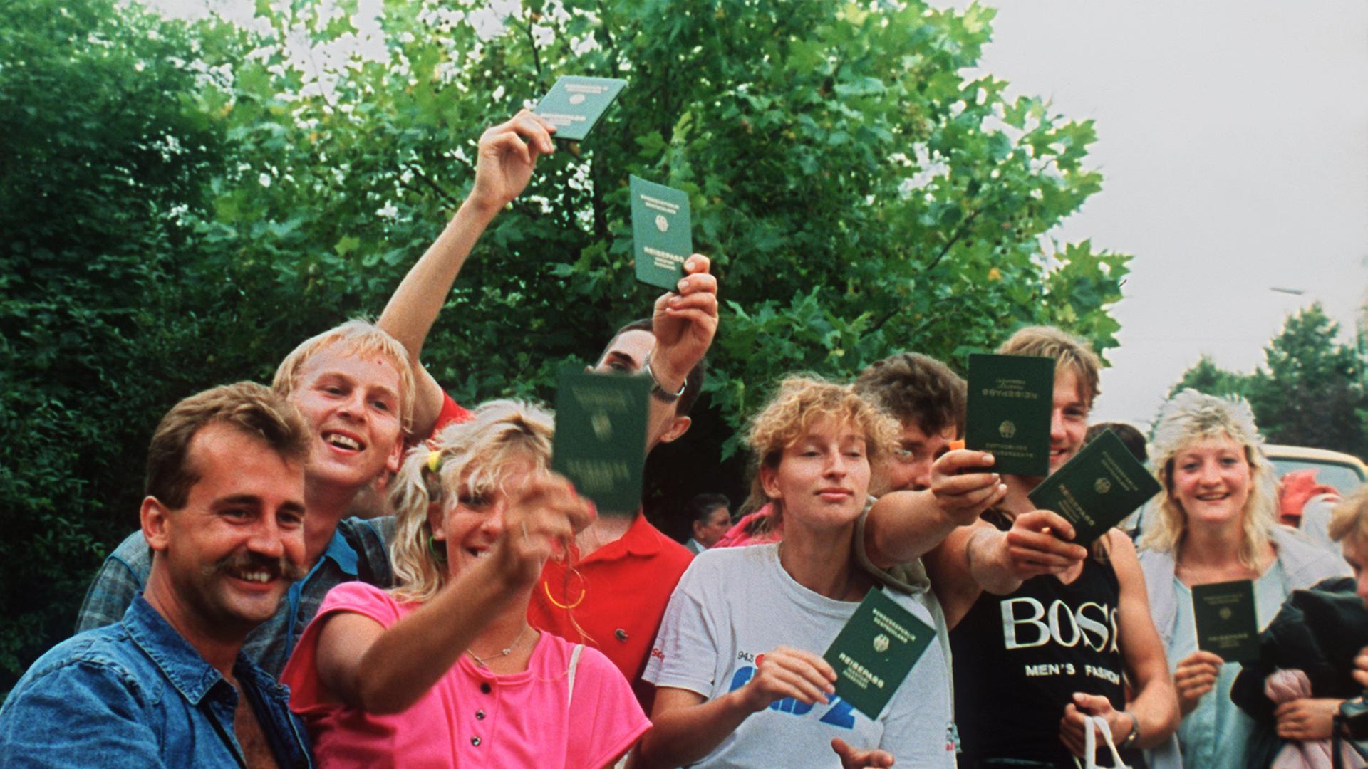 Jubelnde DDR-Flüchtlinge mit ihren Reisepässen in Österreich. Etwa 600 DDR-Bürger nutzten ein paneuropäisches Picknick an der ungarisch-österreichischen Grenze, bei dem ein Grenztor symbolisch geöffnet wurde, zur Flucht in den Westen.
