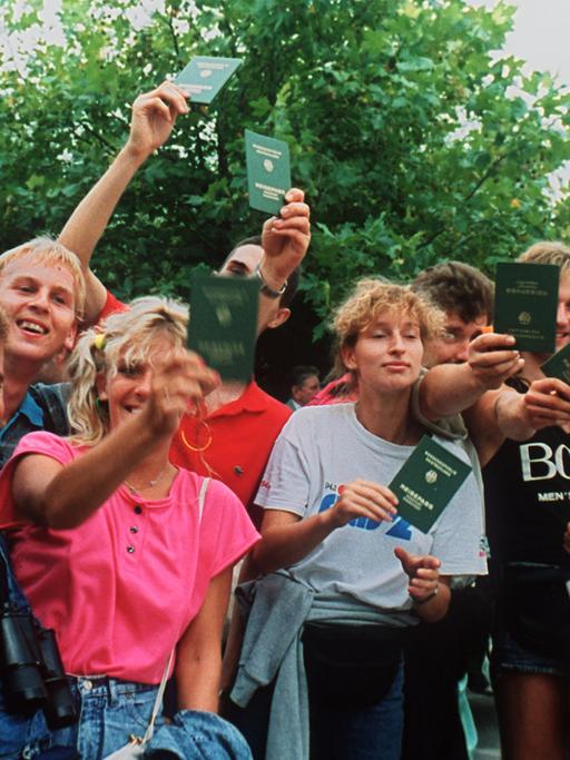 Jubelnde DDR-Flüchtlinge mit ihren Reisepässen in Österreich. Etwa 600 DDR-Bürger nutzten ein paneuropäisches Picknick an der ungarisch-österreichischen Grenze, bei dem ein Grenztor symbolisch geöffnet wurde, zur Flucht in den Westen.
