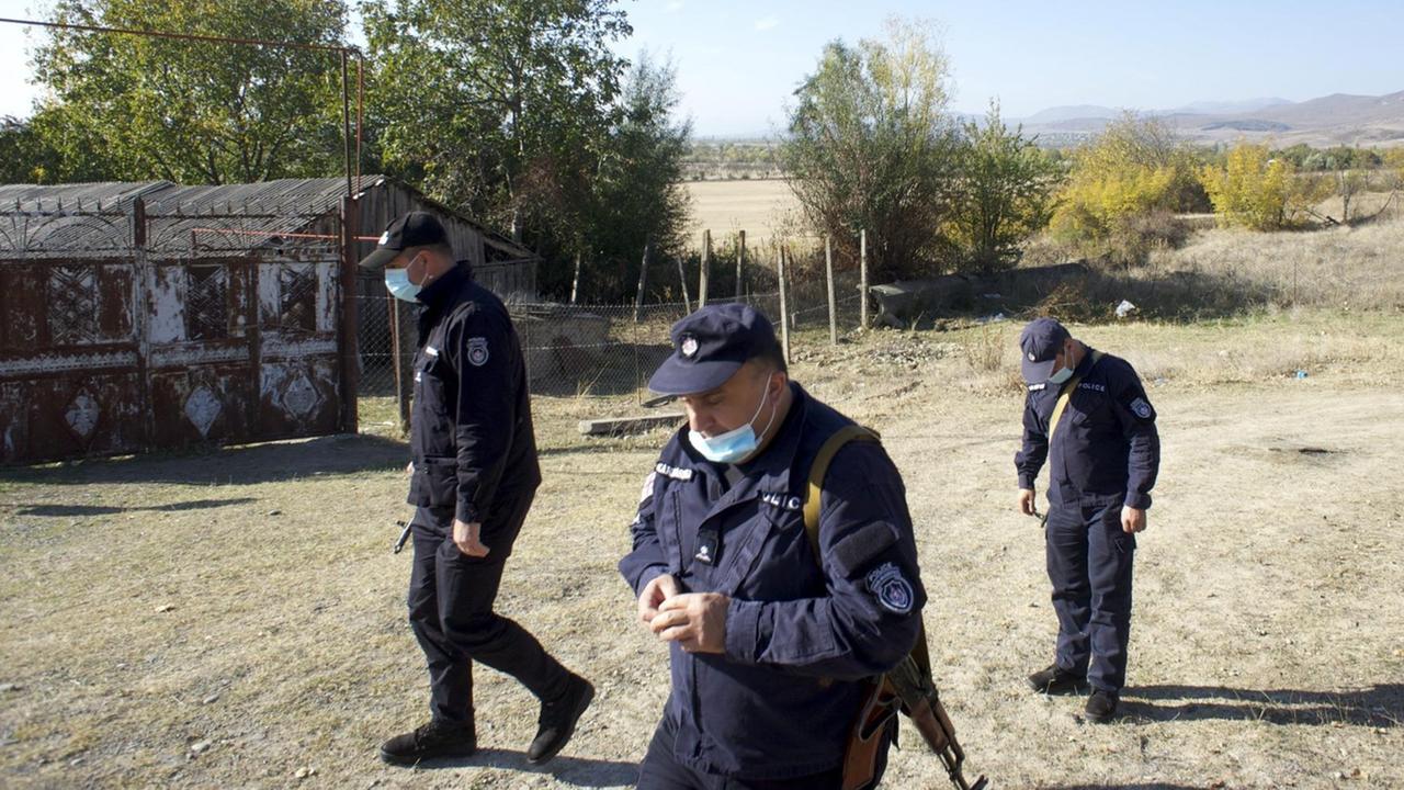 Drei georgische Polizisten in Churwaleti an der Grenze zu Südossetien. Sie gehen in Uniform durch das Dorf.