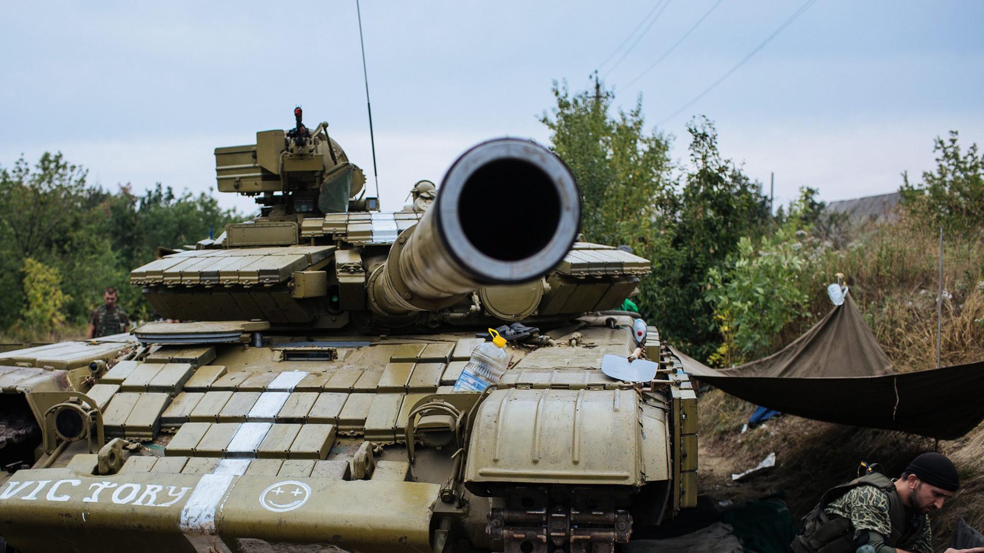 Ein ukrainischer Soldat sitzt neben einem Panzer im Osten der Ukraine.