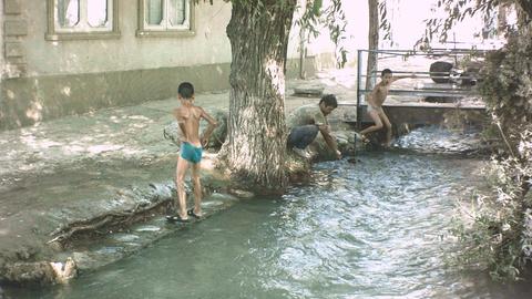 Kinder spielen in den Aryk-Kanälen - den traditionallen Wasserleitungen in Kirgistan, die in allen Städten sind.