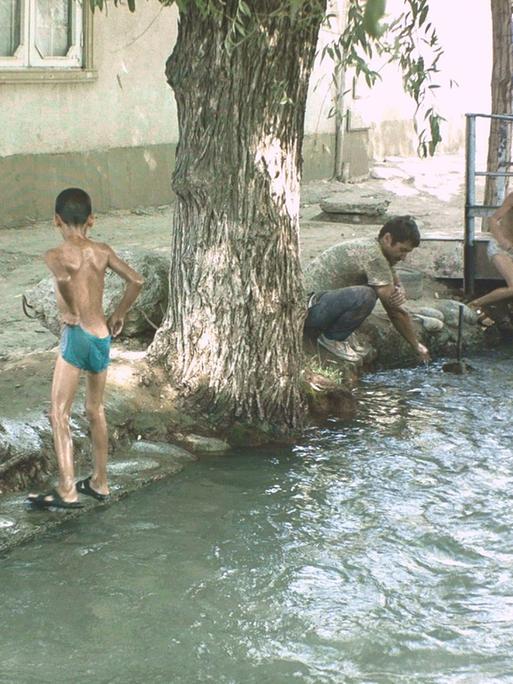 Kinder spielen in den Aryk-Kanälen - den traditionallen Wasserleitungen in Kirgistan, die in allen Städten sind.