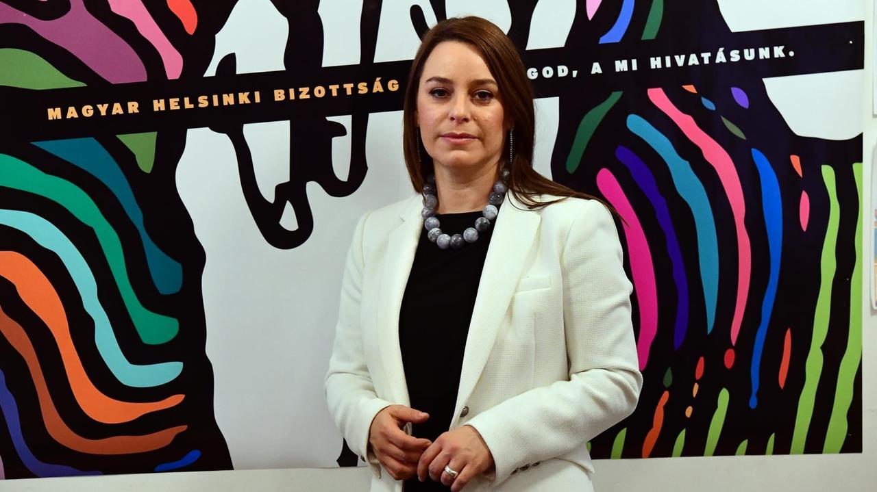Márta Párdavi, Co-Vorsitzende des Budapester Helsinki-Komitees, steht in Budapest vor einem Bild mit dem Schriftzug ihrer Organisation. 
