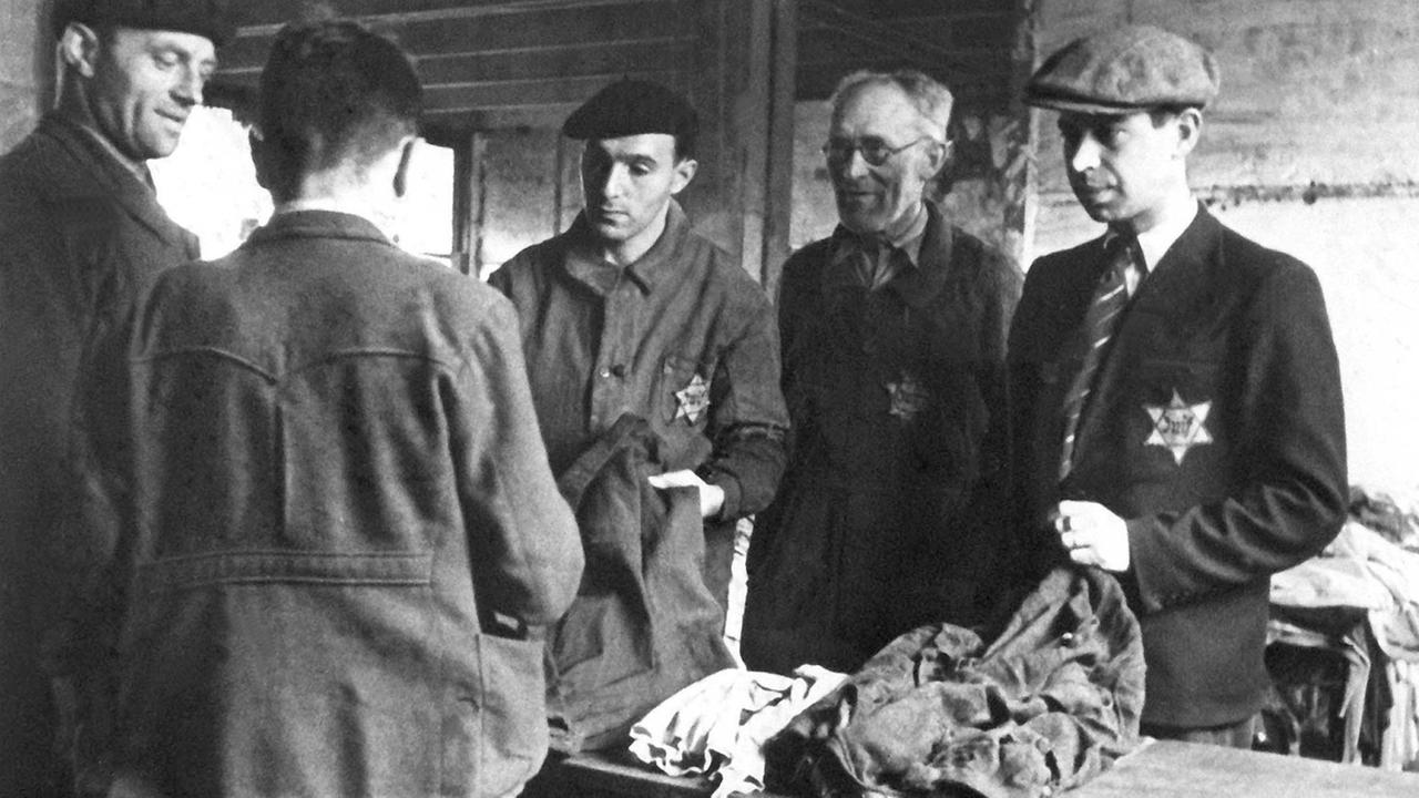 Jüdische Männer mit Davidstern an ihrer Kleidung in einem Internierungslager im französischen Drancy 1942 vor ihrer Deportation in deutsche Konzentrationslager.