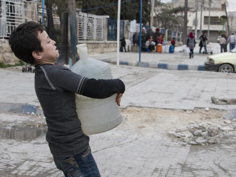 Ein Junge in Aleppo trägt einen Container mit Wasser.