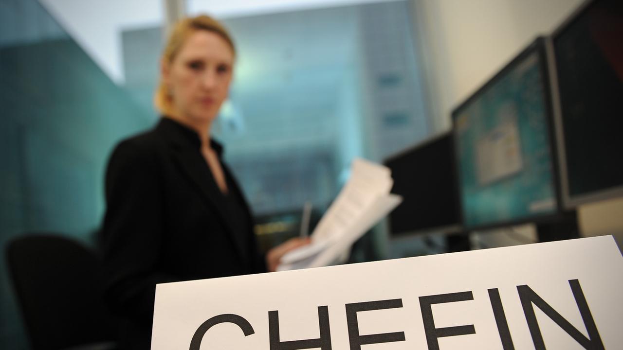 ILLUSTRATION - Eine Frau sitzt am 03.01.2013 an einem Schreibtisch vor einem Computer in einem Büro in Berlin und ließt einen Vertrag. Vor ihr steht ein Schild mit der Aufschrift "Chefin". Foto: Jan-Philipp Strobel/dpa