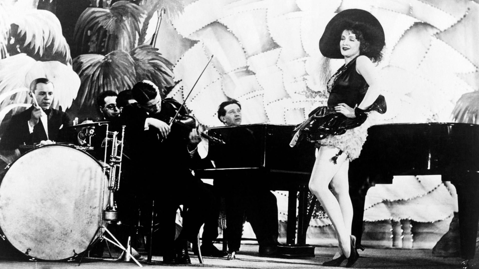 THE BLUE ANGEL, aka DER BLAUE ENGEL, Marlene Dietrich, right, accompanied by Die Weintraub Syncopators, and Friedrich Hollaender, on piano, 1930 Courtesy Everett Collection PUBLICATIONxINxGERxSUIxAUTxONLY Copyright: xCourtesyxEverettxCollectionx MBDBLAN EC111