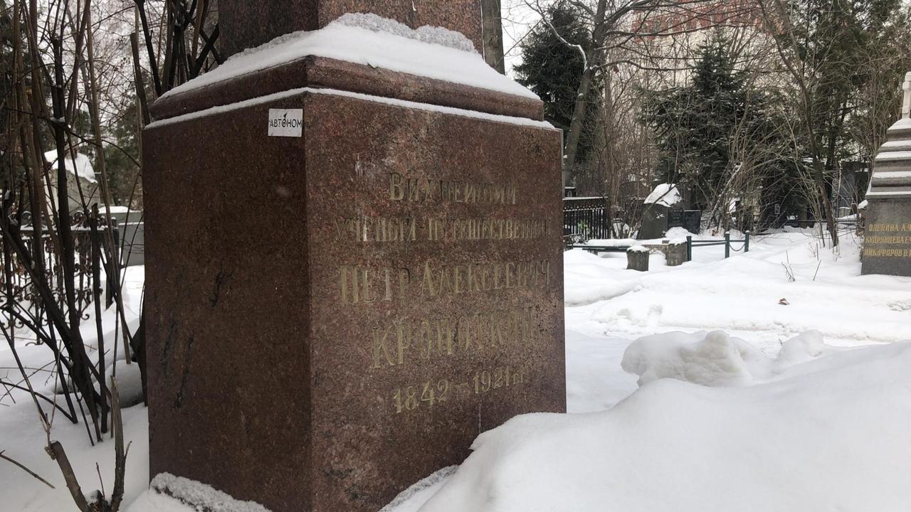 Kropotkins Grabstein auf einem Moskauer Friedhof (brauner Marmor, eingeschneit) - an der Seite ein Aufkleber mit dem russischen Wort für "autonom".