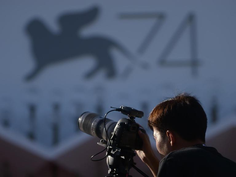 Eine Journalistin steht vor dem Logo der 74. Filmfestspiele in Venedig 2017