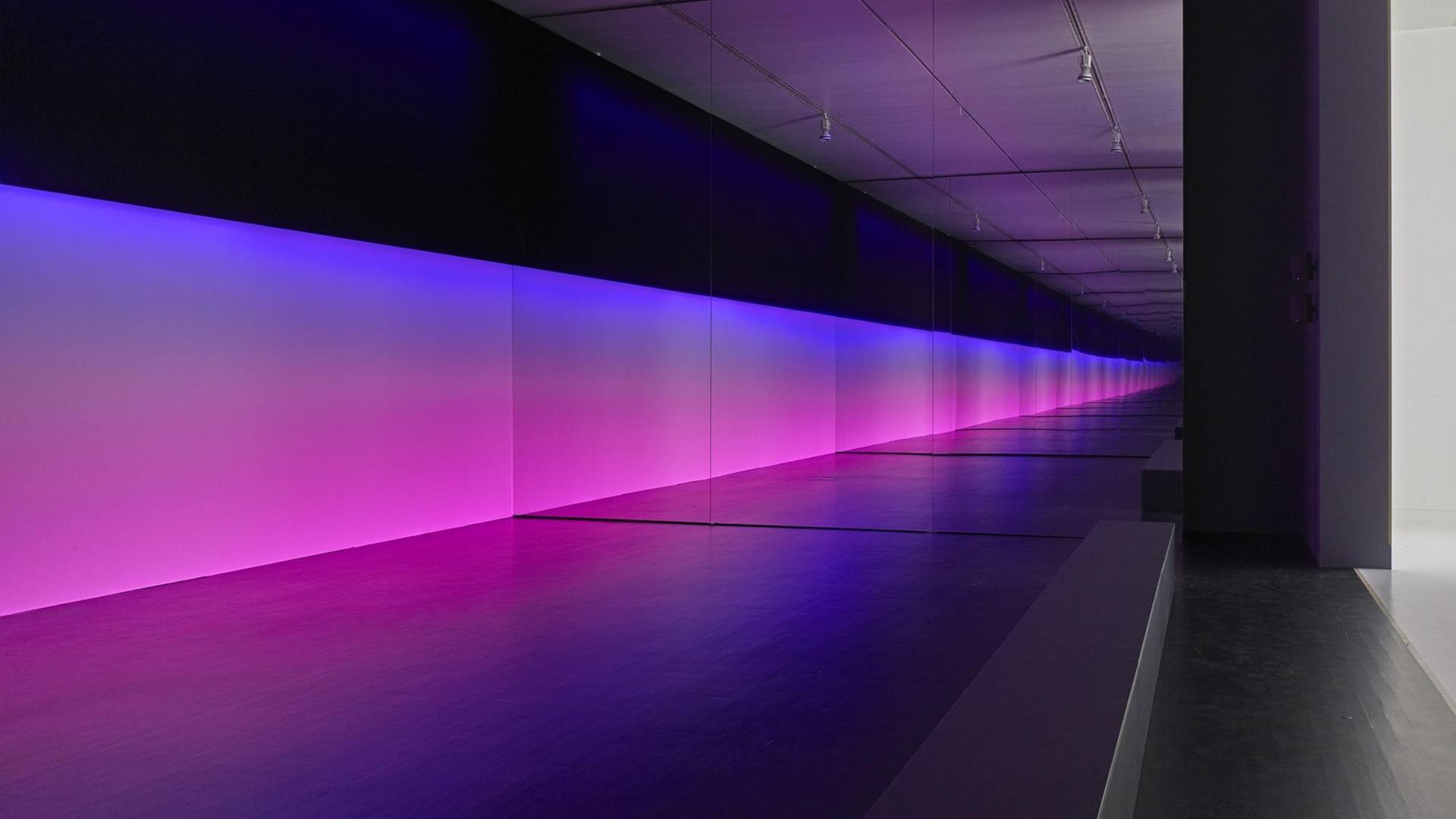 Eine blau-lila Lichtfläche führt durch eine lange Fluransicht. Installationsansicht der Arbeit "unicolor" (2014) von Olaf Nicolai