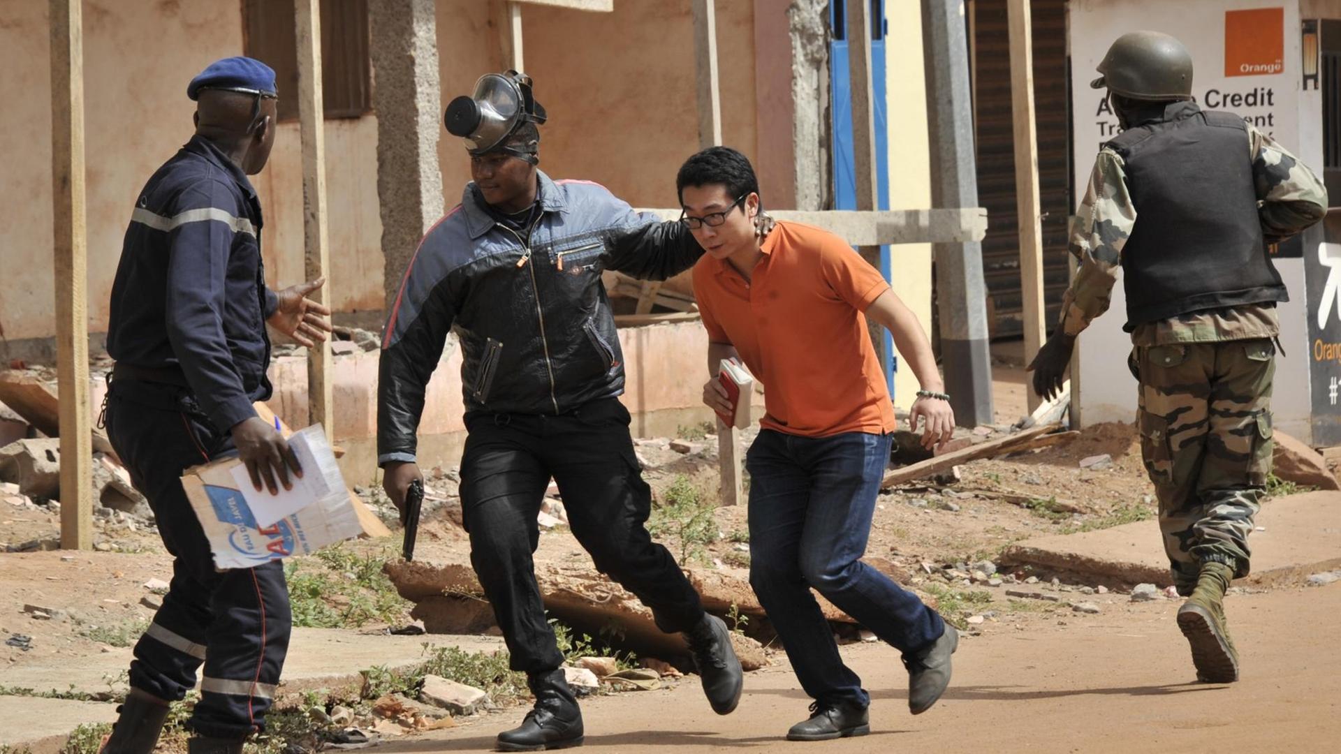 Sicherheitskräfte eskortieren eine Geisel, die aus dem Hotel in Bamako befreit wurde.